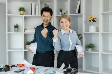 İki farklı mühendis modern bir ofiste, mimari planlamalardaki başarılarını sevinçle kutluyor..
