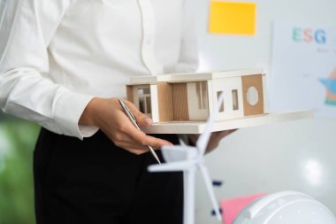 Sürdürülebilir bir yapı modelini sergileyen bir mimar, işbirlikçi bir ortamda çevre dostu tasarım ilkelerini vurguluyor.