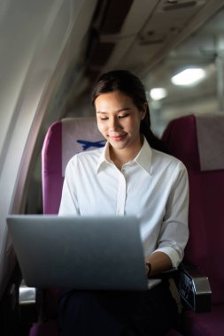 Bir iş gezgini, uzaktan çalışma ve havada üretkenlik örneği olan dizüstü bilgisayarıyla mutlu bir şekilde meşgul olur..