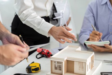 Sürdürülebilir inşaatta işbirliği yapan mimarlar, minyatür bir modeli analiz ederken, eko-sorumluluğu vurgularlar.