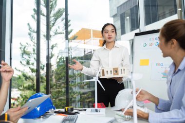 Sürdürülebilir bina tasarımını bir model kullanarak açıklayan mimar, ekolojik bilinçli bir çalışma alanında işbirliğini teşvik ediyor.