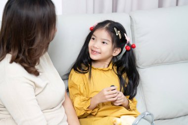 Bir anne ve kızı, sıcak bir yuva ortamında sevgi ve bağlantıyı yansıtan kanepede mutlu bir sohbet ederler..