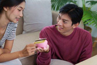 Çift, kumbaralarını elinde tutarken tasarruf hedeflerini tartışarak para yönetimindeki keyif ve sorumluluk karışımını sergileyerek keyifli bir anın tadını çıkarıyor..