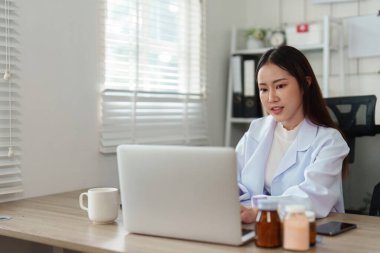 Bir doktor, günümüzde dijital sağlık hizmetlerinin önemini göstermek için hastalara tele-sağlık muayeneleri için dizüstü bilgisayar kullanır..