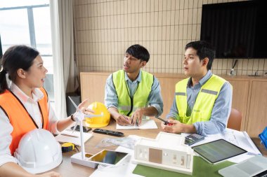 Bir grup mühendis sürdürülebilir bir inşaat projesi planlamak, stratejileri tartışmak ve fikirleri paylaşmak için işbirliği yapıyorlar..