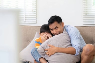 Bir baba, endişeli bir film izlerken, korkmuş oğlunu yanında tutar. Korumacı ilişkilerini vurgular..