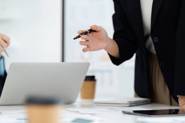 Stratejileri tartışırken, çağdaş bir ofis ortamında takım çalışmasının ve işin önemini vurgularken, kendini işine adamış profesyonel bir jest..