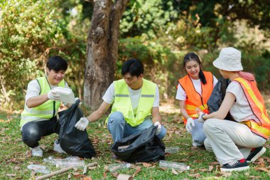 Bir parkta, gönüllüler çöpleri siyah torbalara doldurup, daha temiz bir çevre için toplu eylem ve sürdürülebilir uygulamalara olan bağlılıklarını gösteriyorlar..