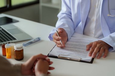 Bir doktor, klinik ortamda güven ve anlayışı artırırken, önemli tıbbi belgeleri gözden geçirir ve bir hastayla iletişim kurar..