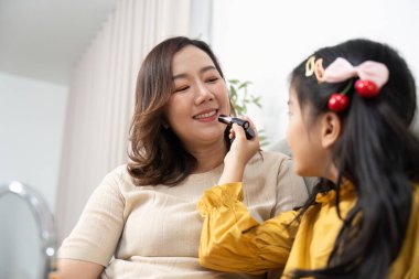 Genç bir kız annesine makyaj yapmaktan zevk alıyor. Gülme ve yaratıcılıkla dolu sevgi dolu bir aile anı yaşıyor..