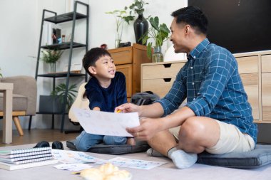 Bir baba ve oğul evde eğlenceli ve eğitici bir eğitim oturumunda aile desteğini ön plana çıkarırlar..
