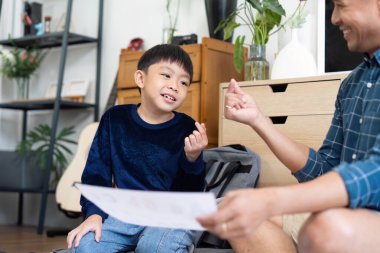 Bir baba ve oğul evde birlikte okurken keyifli bir anı paylaşıyor, eğitimin ve aile bağının önemini vurguluyor..