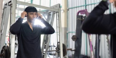 Odaklanmış bir adam egzersiz için kulaklıklarını ayarlar, fitness eğitimine hazırlanır..