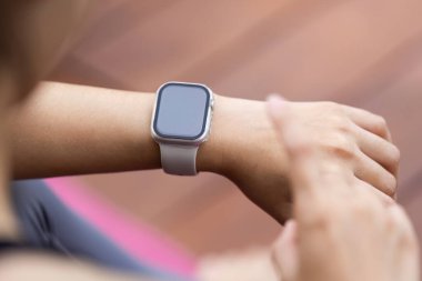 Akıllı bir bilekle süslenmiş genç bir kadın spor ve modern teknolojinin karışımını sembolize ediyor..