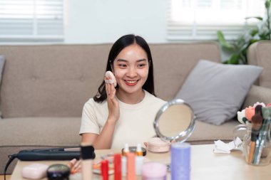 Canlı bir kadın, görünüşünü geliştirmek için etrafını bir dizi güzellik ürünüyle çevreleyen evde sabahları etkili bir şekilde makyaj yapar..
