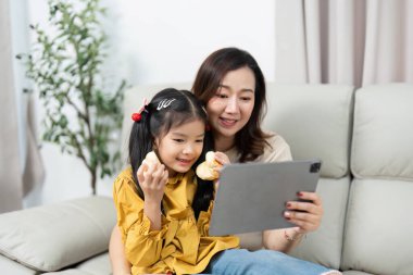 Anne ve kızı bir tabletle meşgul oldukları, yakın ilişkilerini ve modern aile yaşamlarını sergiledikleri keyifli bir anı paylaşıyorlar..