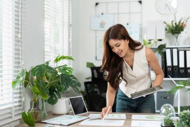 Çevre dostu bir ofis ortamında yeşilliklerle çevrili, iş sürdürülebilirliği planına odaklanmış genç bir kadın..