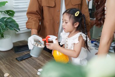 Çevreyi yetiştirmeye hevesli küçük bir kız bitkileriyle ilgilenmek için sprey kullanıyor. Bu sahne, çocuk gelişiminde sürdürülebilirliğin ve çevreci bilincin önemini vurgular.