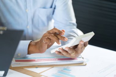 Bir işadamı akıllı telefonunu veri eğilimlerini analiz etmek ve modern ofis ortamında verimliliği artırmak için kullanır..