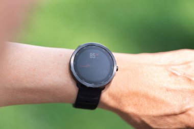 Yaşlılardan birinin bileğindeki akıllı hareket, sağlık izleme ve teknolojinin önemini vurgulayan kalp atış hızı verilerini gösterir..