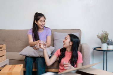 Neşeli, çeşitli bir çift hareketlerini bir bardak suyla kadeh kaldırarak kutluyor. Birlikte bir anlık rahatlığın tadını çıkarıyorlar..