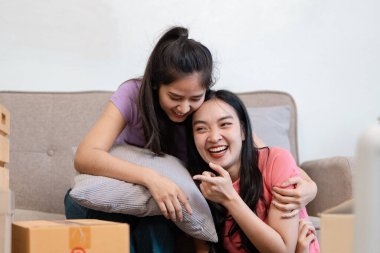 Mutlu, çeşitli bir çift kanepeye uzanır, güler ve kutuları taşırken birbirlerine eşlik ederler..