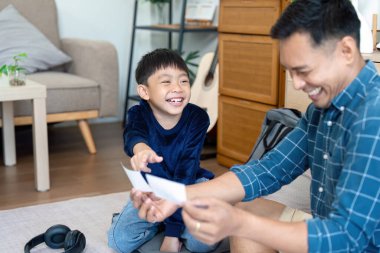 Bir baba ve oğul evde eğlenceli aktivitelere girişerek okula dönüş hazırlıkları için olumlu bir ortam yaratıyor. Kahkahaları ve bağlantıları aile desteğinin önemini vurguluyor.
