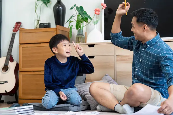 Baba ve oğul okul ödevlerini tartışırken, etkileşimli öğrenme ve aile ilişkisinin önemini vurgulayarak keyifli bir anı paylaşıyorlar..