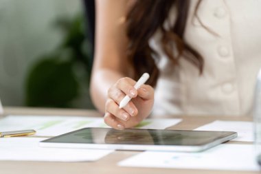 Genç bir profesyonel sürdürülebilir stratejiler belirlemek için bir tablet kullanıyor, teknolojinin eko-dost planlama entegrasyonunu gözler önüne seriyor.