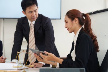 Bir avukat müşteriye dijital belgeleri incelerken rehberlik eder, hukuki senaryolardaki işbirliği ve stratejik planlamayı vurgular.