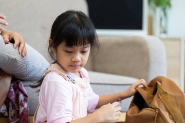 Okuldaki ilk günü için okul malzemeleriyle dolu sırt çantasını hazırlayan genç bir kız..