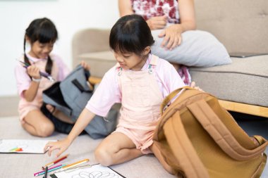 Genç bir kız, kız kardeşi yeni okul yılına hazırlanırken sırt çantasını hazırlamaya odaklanır..