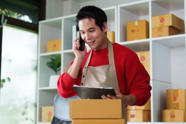 Küçük bir işletme sahibi paketleri yönetirken bir telefon görüşmesi yapar ve başarılı bir iş yürütmek için gereken çoklu görevleri vurgular.