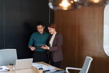 Çağdaş bir çalışma alanındaki iki profesyonel, bir tablet üzerinde proje görüşleri, işbirliği ve öğrenmeyi geliştirme.