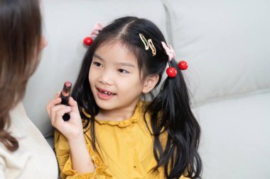 Küçük bir kız, makyajı keşfederken annesiyle şakalaşıyor. Neşeli ilişkilerini ve aile ilişkilerinin eğlencesini yansıtıyor..