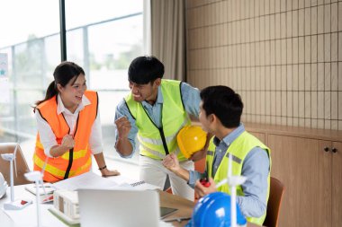 Mühendislik ekibi yeşil teknolojideki başarılarını kutluyor, modern ofis ortamında coşku ve takım çalışması sergiliyorlar..