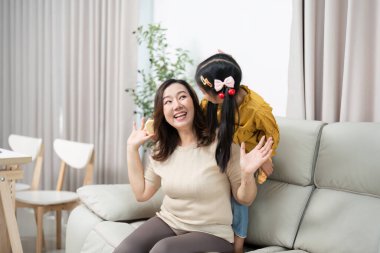 Bir anne kızıyla oynaşmaktan zevk alır, yakın bağlarını ve mutluluğunu sıcak bir oturma odasında gösterir..