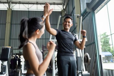 Neşeli bir antrenör ve kadın antrenman başarılarını spor salonunda beşlik çakarak, takım çalışmasını ve motivasyonunu göstererek kutluyor..