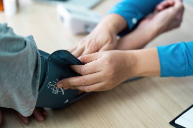Bir sağlık uzmanı, hastaların tansiyonlarını monitör kullanarak kontrol eder. Klinik ortamda düzgün bir sağlık değerlendirmesi sağlar..