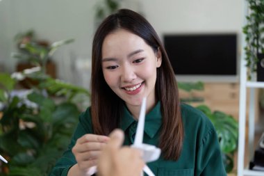 Bir kadın rüzgar enerjisi modeli üzerinde çalışırken gülümsüyor, sürdürülebilir bir projede işbirliği ve yenilik gösteriyor.