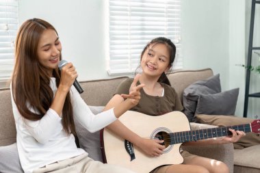 Bir anne ve kızı neşeli bir müzik deneyimi yaratıyor, anne şarkı söylüyor ve kız ona gitarda eşlik ediyor, aile bağlarını güçlendiriyor..