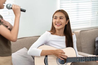 Bir anne gitarını çalar ve kızı mikrofona şarkı söyler. Müzikal yeteneklerini ve aile eğlencesinin neşesini gösterir..