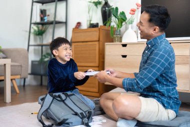 Bir baba oğluyla keyifli bir anı paylaşırken okul malzemelerini bir araya toplar, takım çalışmasını ve mutluluğu destekler..