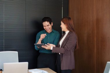 Ofis ortamında çalışan iki profesyonel, takım çalışmasının ve yeniliğin gücünü vurgulayan bir tablet üzerinde verimli bir tartışmaya giriştiler..