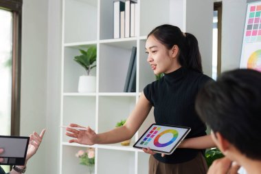 Yetenekli bir tasarımcı, tablet kullanan yenilikçi UX UI kavramlarını sunar, takımı tasarım seçenekleri üzerine bir tartışmaya sokar..