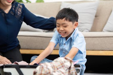 Çocuk, annesinin yaklaşan seyahat planlarını merakla beklediği bavullarını toplamasına sevinçle yardım ediyor..