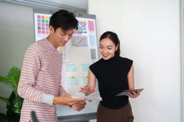 İki grafik tasarımcısı basılı tasarımlar hakkında fikir ve içgörülerini paylaşırken, diğer tasarımcı dijital araçlara odaklanıyor, tasarımda takım çalışması sergiliyor.