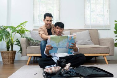 Çift, seyahat güzergahlarını ve varış noktalarını tartışırken beklentiyle dolu bir haritayı incelemek için yerde birlikte oturuyor..