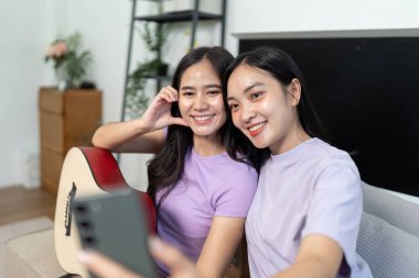 Neşeli bir LGBTQIA çifti birlikte müzik dinlerken eğlenceli bir selfie çekiyor, bağlarını ve mutluluklarını sergiliyorlar..