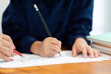 İki çocuk, yaratıcılıklarını göstermek için renkli kalemler ve çizim araçları kullanarak sanat projelerinde işbirliği yapıyorlar. Bu sahne okula dönüş hazırlıklarının heyecanını yakalıyor..